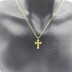 Detailed view of a gold beaded cross pendant on an elegant minimalist chain necklace