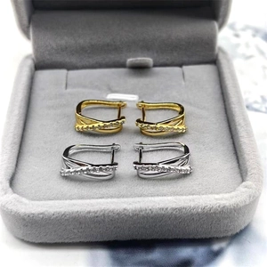 Détail de boucles d'oreilles créoles croisées argentées et dorées avec oxydes de zirconium
