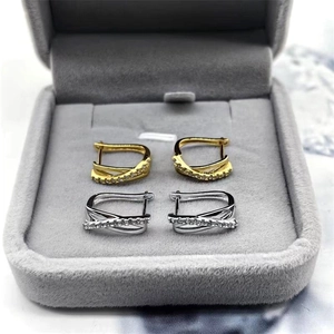 Détail de boucles d'oreilles croisées en argent S925 doré et argenté avec zircons