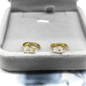 Détails de boucles d'oreilles dorées avec zircone poire dans un écrin à bijoux en velours gris