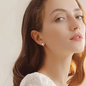 Close-up of S925 sterling silver geometric earrings with sparkling zircon on model ear