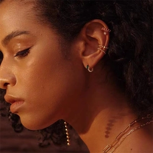 Gros plan de manchettes d'oreille dorées et boucles d'oreilles goutte avec pierre verte