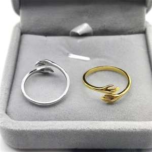 Close-up of gold and silver embrace hands rings presented in a velvet jewelry box