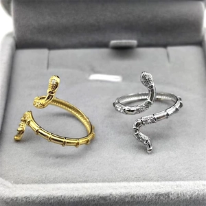 Détail macro de bagues serpent en or et argent avec zircons blancs sur velours gris