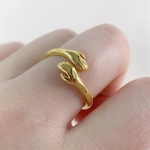 Close-up of a golden S925 sterling silver hugging hands ring worn on a model finger