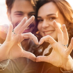 Close-up of S925 sterling silver hug ring worn by a couple forming a heart shape