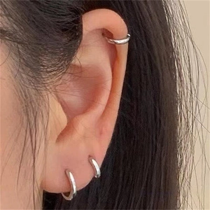 Close-up of minimalist S925 sterling silver hoop earrings worn on earlobe and cartilage