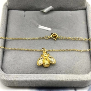 Detailed view of a gold bee pendant necklace with pavé stones on a velvet display