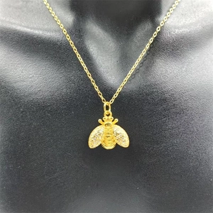 Macro view of gold bee pendant with sparkling cubic zirconia on a black bust display