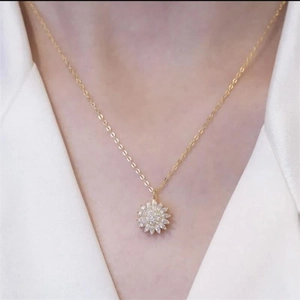 Detail van de fonkelende zonnebloem hanger ketting met zirkonen aan een gouden kettinkje