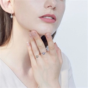 Detailed close-up of a silver S925 sterling silver evil eye ring and star earring on a model