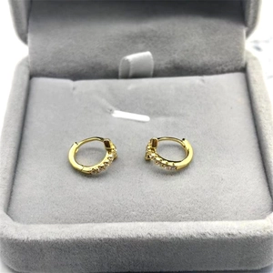Detailed view of gold V-shaped huggie earrings with sparkling pavé cubic zirconia