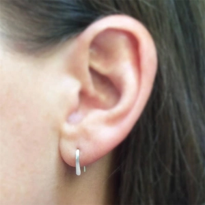 Close-up of minimalist S925 sterling silver curved line earring worn by a model