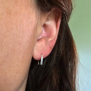 Side view detail of S925 sterling silver minimalist hoop earring worn on a model's ear