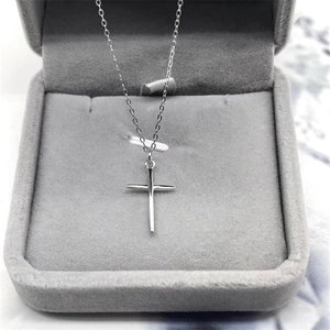 Close-up of a silver S925 cross pendant necklace inside a grey velvet jewelry box