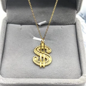 Vue macro du pendentif signe dollar avec zircons sur une boîte en velours gris