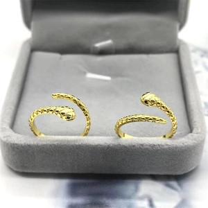 Macro detail of gold snake rings with scale texture and black stones on velvet box