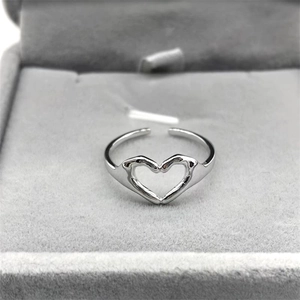 Macro shot of silver hands forming a heart shape on an adjustable minimalist ring