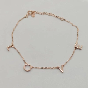 Détail des breloques LOVE en argent sterling S925 doré rose sur un bracelet à chaîne délicate