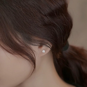 Macro detail of square micro-paved cubic zirconia stud earring on model ear lobe