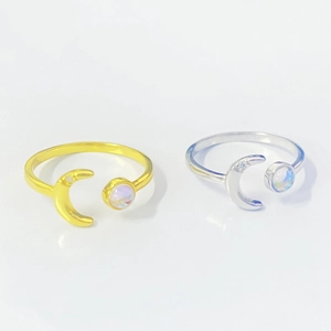 Detail of silver and gold moonstone rings featuring crescent moon and round stone inlay
