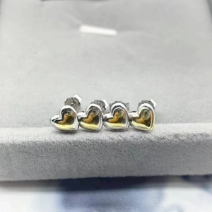 Macro detail of silver heart stud earrings displayed on a grey velvet jewelry tray