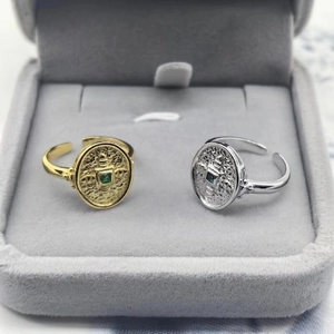 Detail of vintage shield rings with green stones and hammered texture on velvet tray
