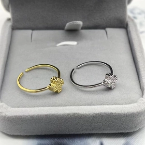 Detail of silver and gold rings with geometric cube cross design in a gray jewelry box