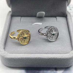 Macro detail of textured gold and silver rings with green gems in a gray jewelry box