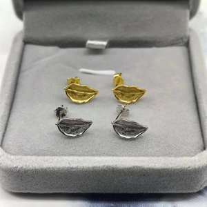 Macro shot of S925 sterling silver leaf stud earrings in gold and silver finishes