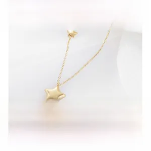 Gros plan de pendentifs étoiles dorées sur chaîne en argent 925 avec fond en tissu doux