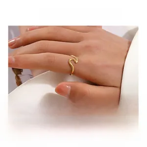 Macro detail of minimalist gold wavy ring with polished finish on model hand
