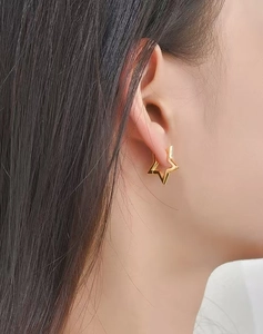 Vue macro d'un mannequin portant des boucles d'oreilles créoles en étoile dorée élégantes