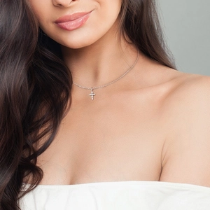 Close-up of S925 sterling silver cross necklace with sparkling diamonds on female model