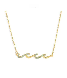 Macro detail of wave-shaped golden necklace with blue pavé zircons on silver chain