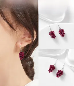 Macro detail of handmade 925 silver grape drop earrings with deep purple garnet beads