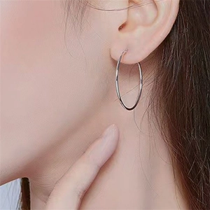 Minimalist sterling silver hoop earrings shown on a model with a clean side profile