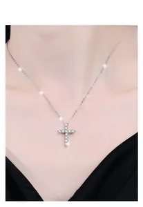 Gros plan d'un collier croix en argent sterling 925 avec zircons porté par un mannequin