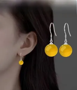 Detail view of ethnic S925 silver hook earring featuring a polished yellow agate bead charm