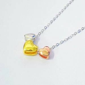 Close-up of three-tone S925 sterling silver heart pendants in silver, gold, and rose gold