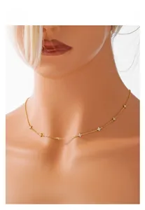 Dettaglio di una collana a quadrifoglio dorata minimalista su un modello per lo stile