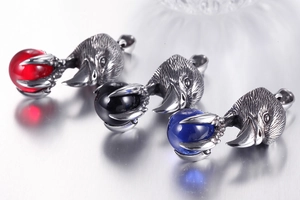 Détail de trois pendentifs griffe d'aigle tenant des perles rouges, noires et bleues