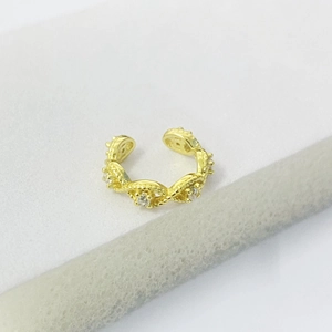 Détail d'un ear cuff doré en forme de C avec texture en relief et zircons brillants