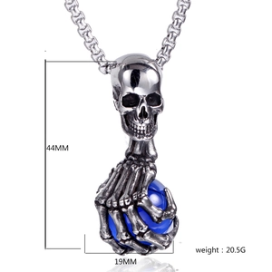 Détail macro d'un pendentif tête de mort gothique avec griffe et sphère bleue