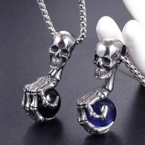 Pendentif crâne gothique avec griffes et pierres obsidienne et bleues sur chaîne carrée