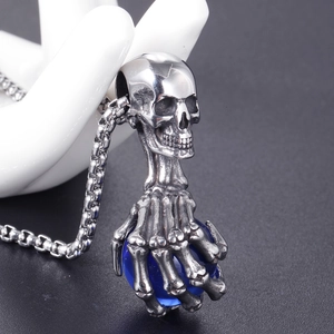 Détail macro du pendentif crâne et griffe de fantôme tenant une perle bleue translucide