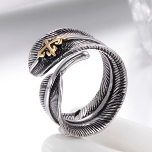 Macro detail of vintage silver feather ring featuring a golden cross totem emblem