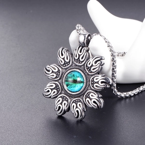 Vintage stainless steel sun pendant necklace with blue evil eye stone on a hand display