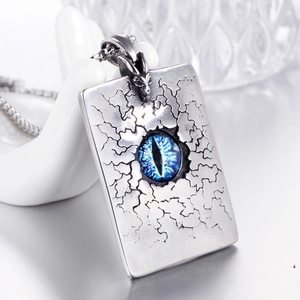Vue macro du pendentif dragon en acier avec œil bleu sur une plaque rectangulaire