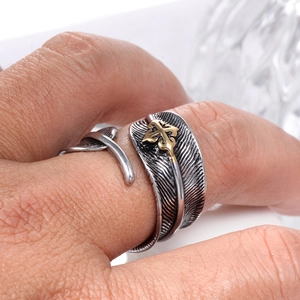 Macro shot of retro feather open ring with golden cross detail and textured finish
